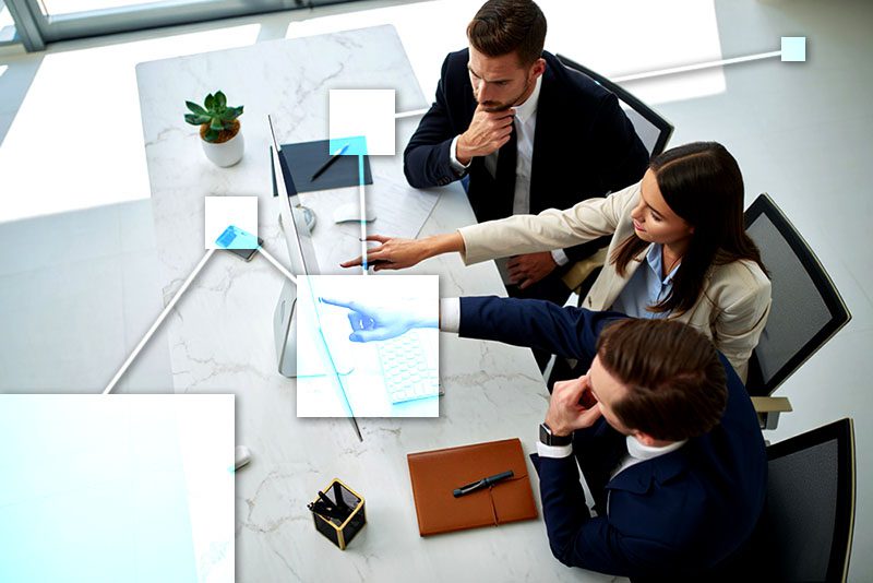 Three employess analyzing financial and inventory reports using TVI business management software.