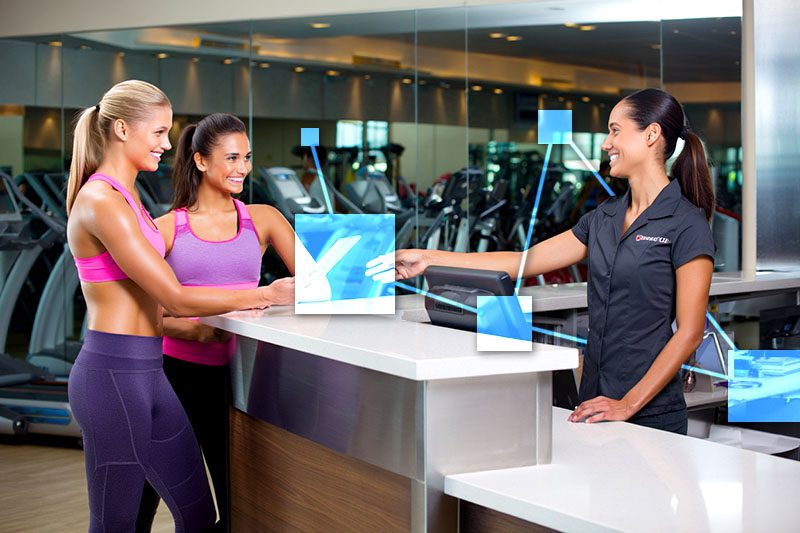 Gym members checking in at front desk at another franchise location using TVI multi-location CRM and POS. 