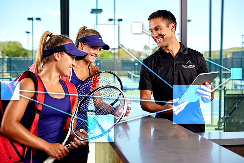 Tennis club receptionist at front desk checking in guests on a corporate guest account using TVI POS and CRM integrated business management software.